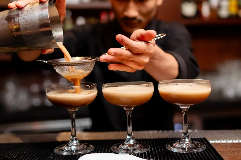 Bartender mixing a cocktail in a bar setting with moody, cinematic lighting
