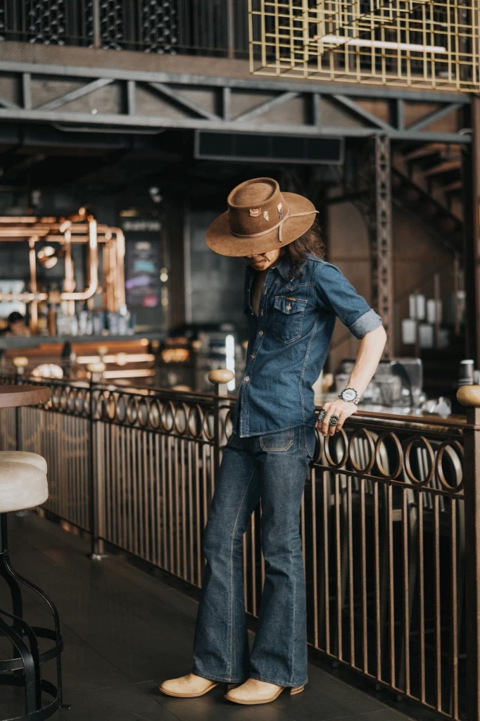Lifestyle portrait in a cafe featuring a cowboy-inspired outfit with moody editorial tones
